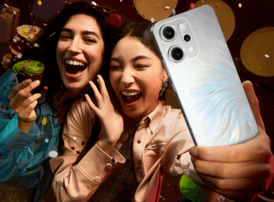 สองสาวกำลังถ่ายเซลฟี่ด้วยสมาร์ทโฟน OPPO Reno14 Pro ในบรรยากาศงานปาร์ตี้ที่เต็มไปด้วยสีสัน แสดงถึงประสิทธิภาพกล้องของรุ่นที่เปรียบเทียบในบทความ OPPO Reno14 Pro vs vivo V60