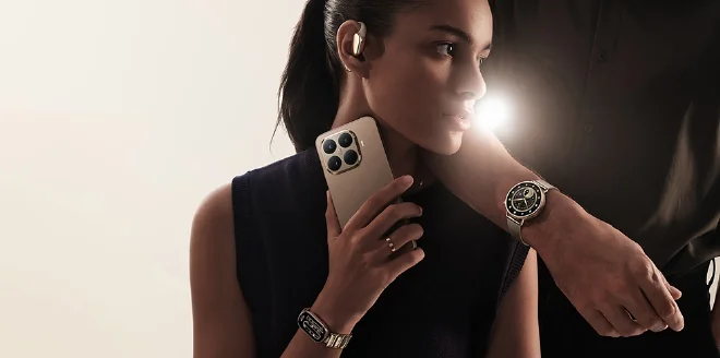 รูปภาพหญิงสาวกำลังถือสมาร์ทโฟน Xiaomi สีทอง พร้อมแสดงอุปกรณ์เสริมอื่น ๆ เช่น หูฟังไร้สายและสมาร์ทวอทช์ ประกอบบทความ ประวัติแบรนด์ Xiaomi