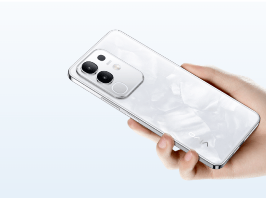 ภาพถ่ายด้านหลังโทรศัพท์มือถือ vivo สีขาวมุกที่กำลังถืออยู่ในมือ แสดงดีไซน์กล้องคู่และแฟลชวงแหวน เหมาะสำหรับบทความเปรียบเทียบคุณสมบัติของ vivo Y29 vs Y28