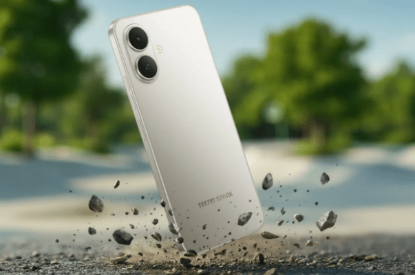 5 เหตุผลที่คนเลือก TECNO มากกว่าแบรนด์อื่น: ภาพระยะใกล้ของโทรศัพท์มือถือ TECNO Spark สีขาว/เงิน ด้านหลังเครื่องกำลังตกลงบนพื้นดินที่มีก้อนหินกระเด็นขึ้นมา แสดงถึงความทนทานของตัวเครื่อง