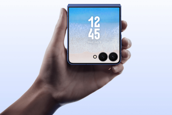 HUAWEI vs Samsung - ภาพมือถือ Samsung Galaxy Z Flip (รุ่นฝาพับ) สีน้ำเงินถูกถืออยู่ในมือ โดยแสดงหน้าจอด้านนอก (Cover Screen) ที่มีพื้นหลังเป็นทะเลและแสดงเวลาและวันที่ พร้อมกล้องคู่ ซึ่งเป็นตัวแทนของดีไซน์พับได้ของ Samsung ในการเปรียบเทียบ HUAWEI vs Samsung