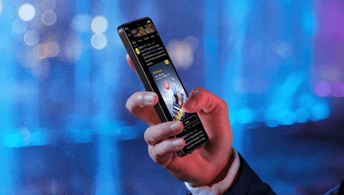 รูปภาพมือที่กำลังถือสมาร์ทโฟน POCO X7 PRO ในแนวตั้งเพื่อใช้งานโซเชียลมีเดียหรือดูฟีด โดยมีฉากหลังเป็นไฟโบเก้สีฟ้าและม่วงในเวลากลางคืน ใช้ประกอบการ รีวิว POCO X7 PRO ในส่วนการใช้งานทั่วไป