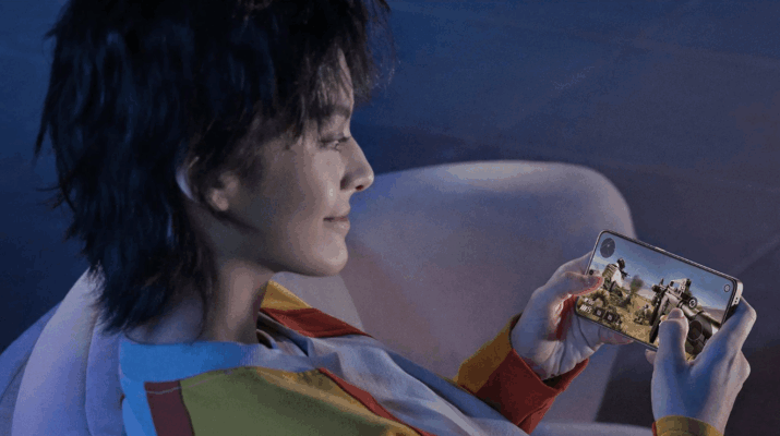 ผู้หญิงกำลังนั่งเล่นเกมยิงปืนบนสมาร์ทโฟนในเวลากลางคืน ภาพสื่อถึงประสบการณ์เล่นเกมที่ลื่นไหลบนมือถือ POCO vs Redme เหมาะสำหรับเกมเมอร์ที่กำลังมองหามือถือสำหรับการเล่นเกม