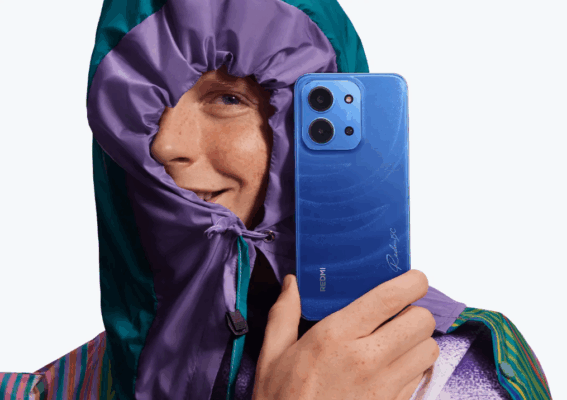 ชายสวมเสื้อกันหนาวมีฮู้ดสีม่วง/เขียว ถือโทรศัพท์ Redmi 15C สีน้ำเงินด้านหลังที่มีลวดลายคลื่นชัดเจนและโมดูลกล้องหลังคู่ สำหรับการ รีวิว Redmi 15C