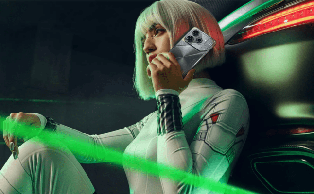 หญิงสาวในชุดสีขาวสไตล์ล้ำยุค (Cyberpunk) กำลังถือโทรศัพท์มือถือ TECNO POVA 6 Pro สีเทาเงิน ที่โดดเด่นด้วยดีไซน์ของโมดูลกล้อง ภาพนี้สื่อถึงสมาร์ทโฟนเกมมิ่งที่มีสไตล์ ซึ่งเป็นหนึ่งในรุ่นหลักที่นำมาเปรียบเทียบในบทความ TECNO POVA 6 Pro vs Infinix GT 20 Pro