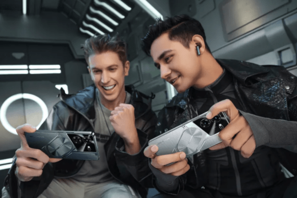 รีวิว TECNO Pova 5 Pro 5G – ชายสองคนกำลังสนุกกับการเล่นเกมบนโทรศัพท์มือถือ TECNO Pova 5 Pro 5G ในดีไซน์ Mecha สีดำและสีเงิน เพื่อเน้นคุณสมบัติการเป็นมือถือเกมมิ่ง
